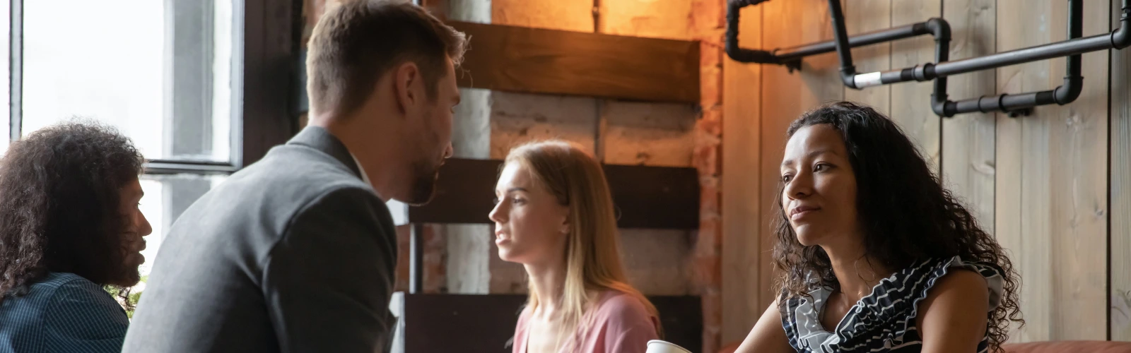 kostenlose-partnersuche-gruppe-kennenlernen Vier Personen sitzen zusammen und unterhalten sich in einem Café, symbolisierend das Kennenlernen von Singles.